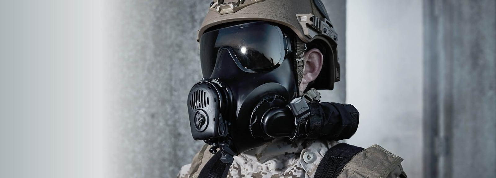Soldier in a helmet wearing a black Avon FM53 mask with a side-mounted filter