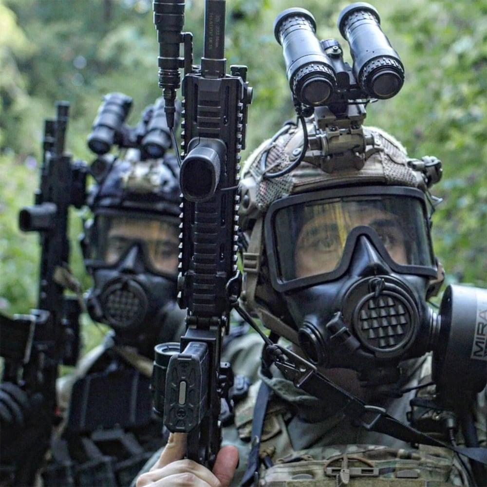 Two soldiers in helmets wearing CM-8M masks and holding rifles