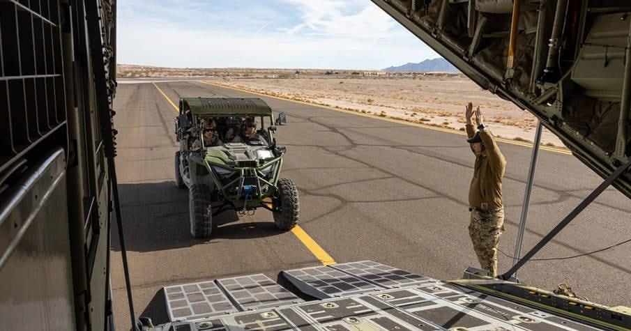 MRZR Alpha driving toward the open ramp of a transport aircraft on a runway