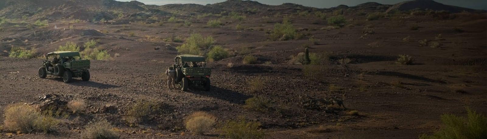 Two MRZR Alpha vehicles crossing dark desert terrain