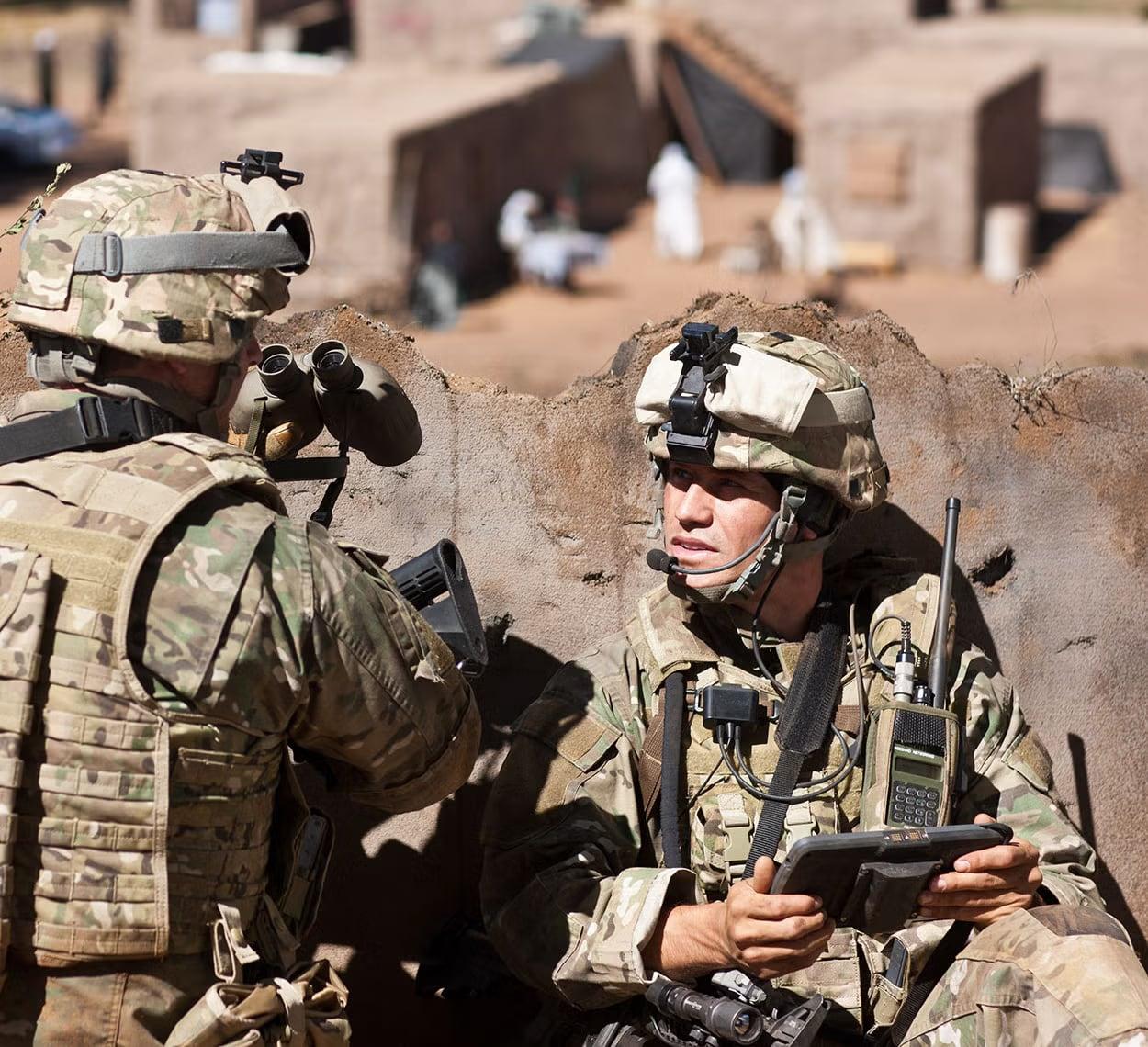 Soldiers in the field with a handheld radio and tablet