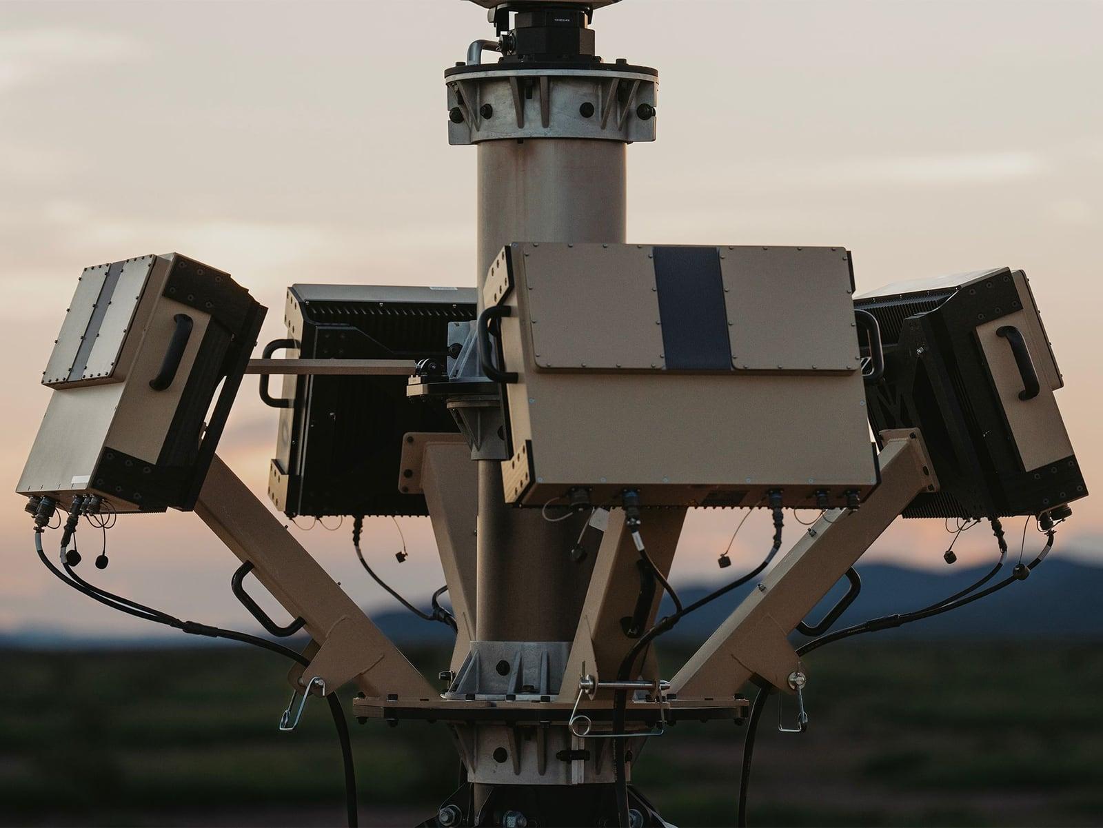 A mast carrying four radar panels in a cross configuration against a dusk sky