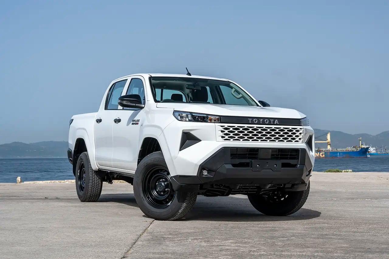 White Toyota Hilux double cab pickup parked on a quayside with the sea behind it